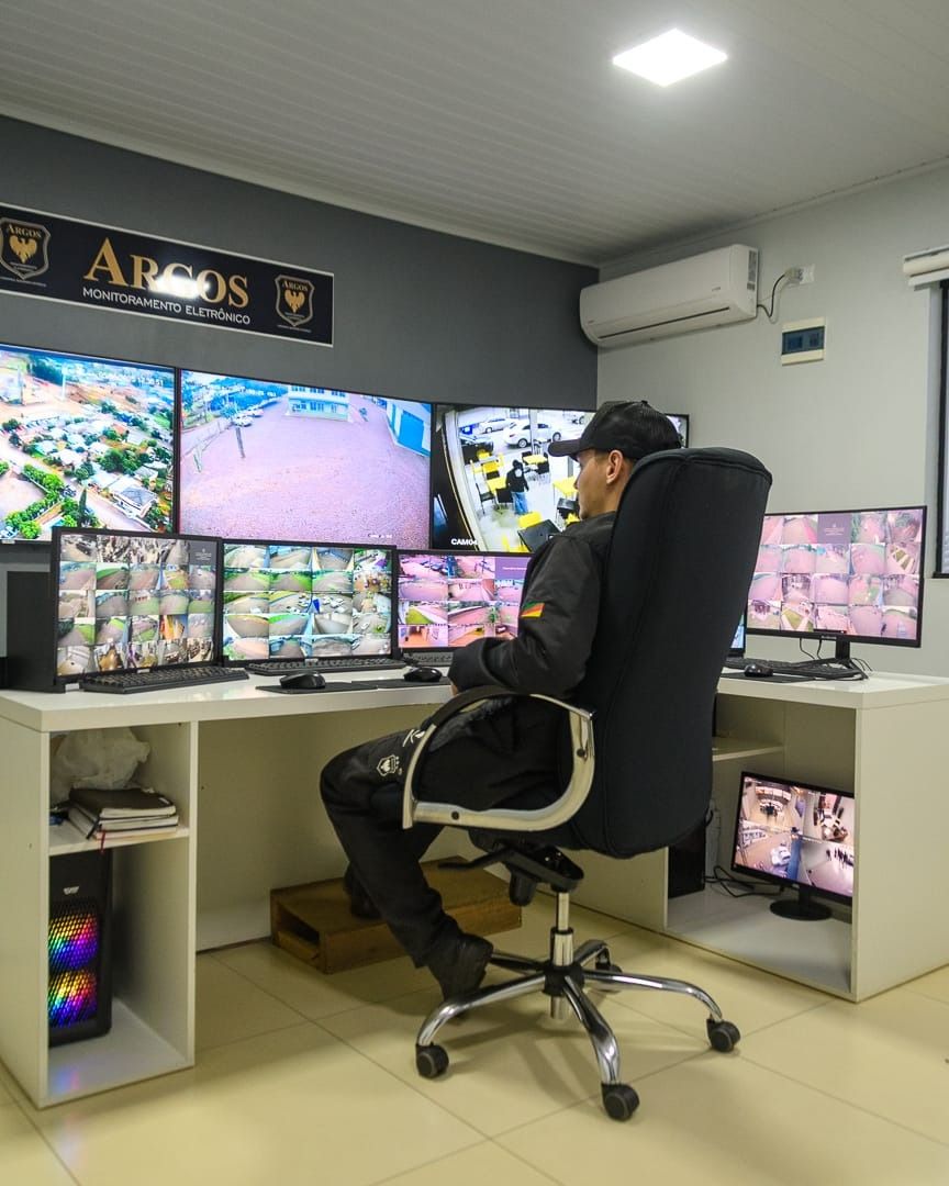 Central de monitoramento da Argos com vários monitores e operador acompanhando as câmeras em tempo real